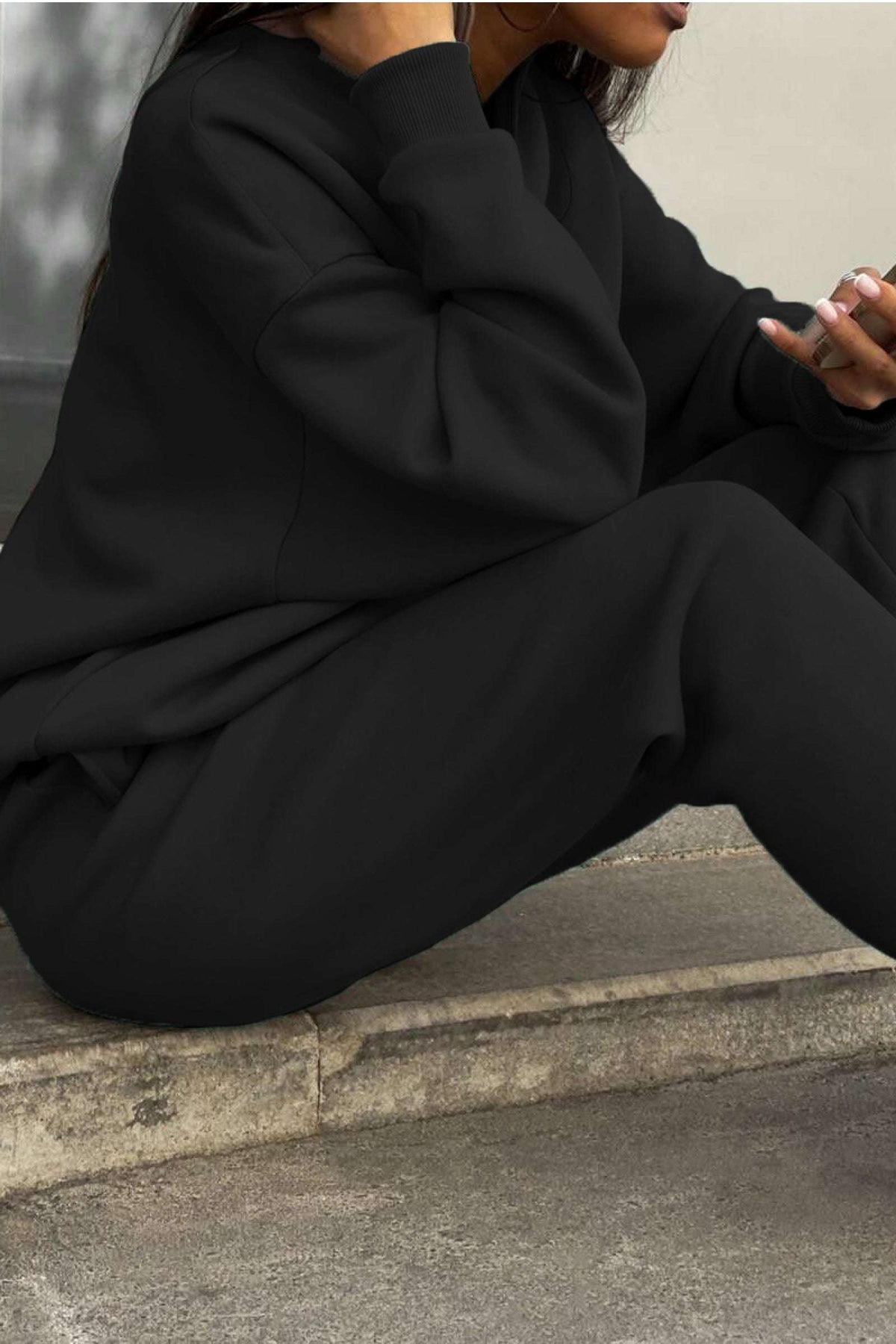 Woman wearing black cotton blend tracksuit with relaxed fit sitting outdoors