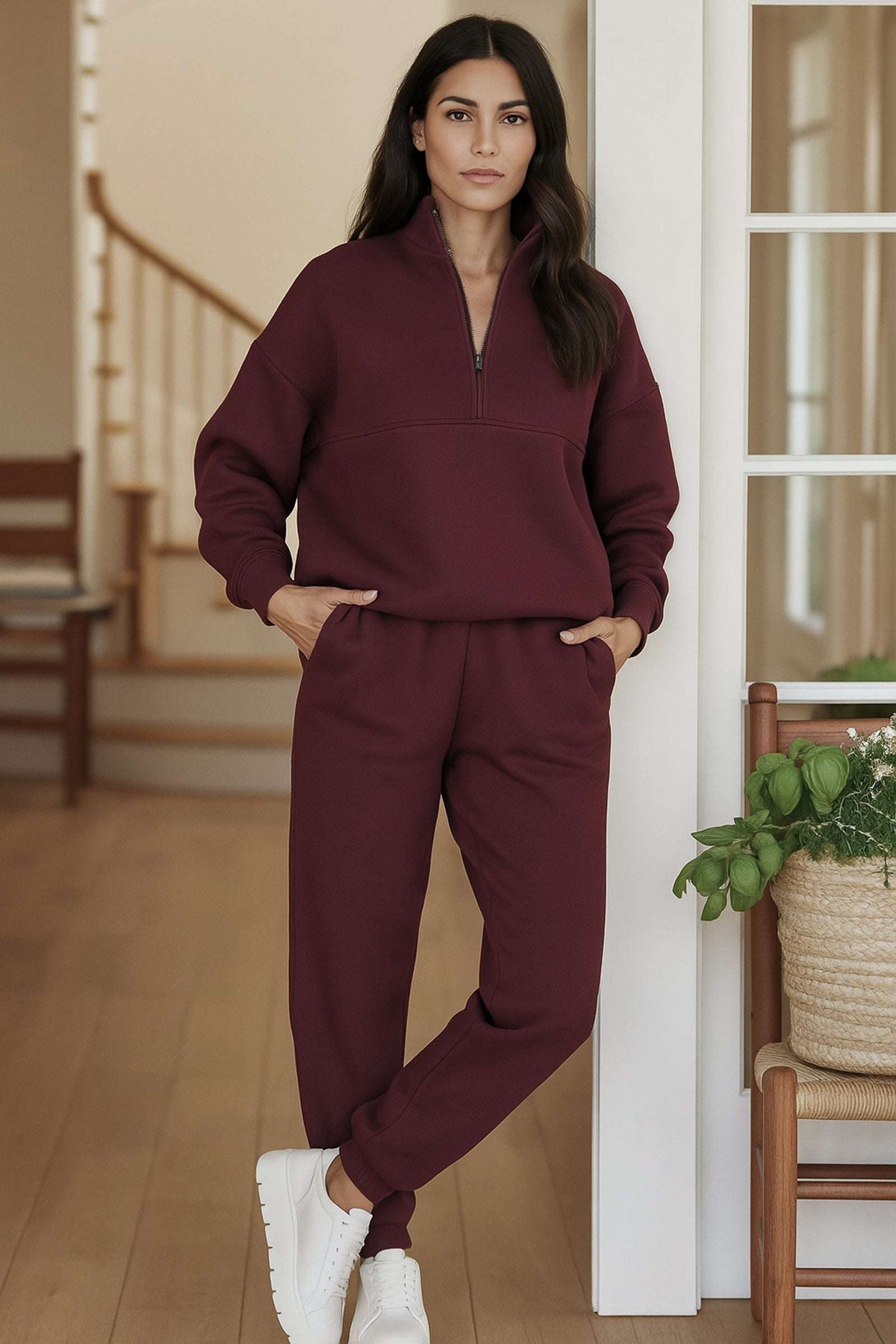 Woman wearing burgundy cotton blend tracksuit with zip neckline and relaxed fit in modern home interior