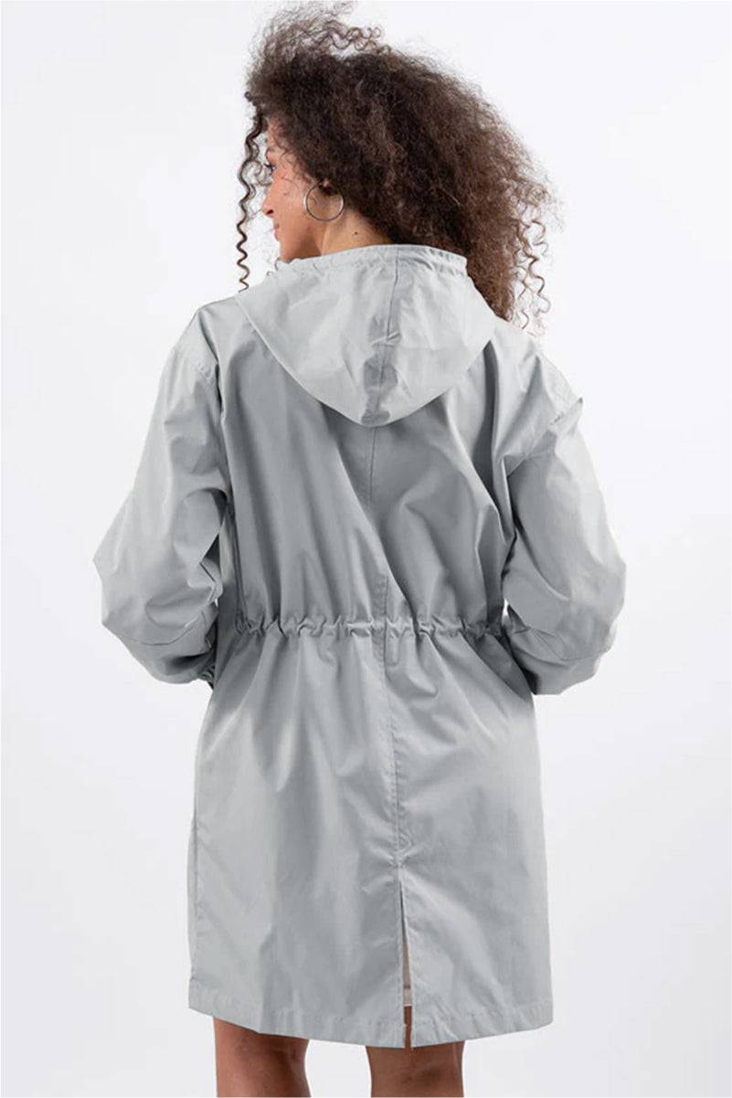 Woman wearing oversized grey Rain Couture Windbreaker with adjustable hood and cinched waist, back view