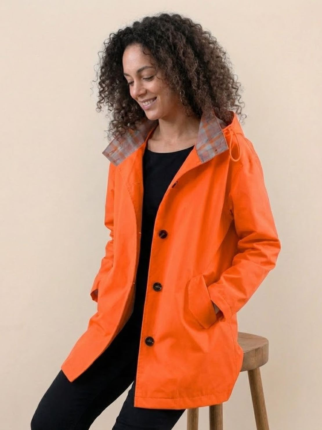 Woman wearing trendy oversized orange Rain Couture Windbreaker jacket with hood and pockets