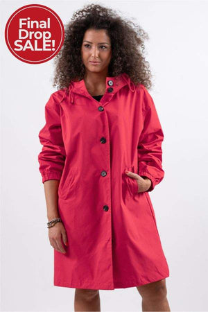 Woman wearing red Rain Couture Windbreaker oversized water-resistant jacket with hood and pockets