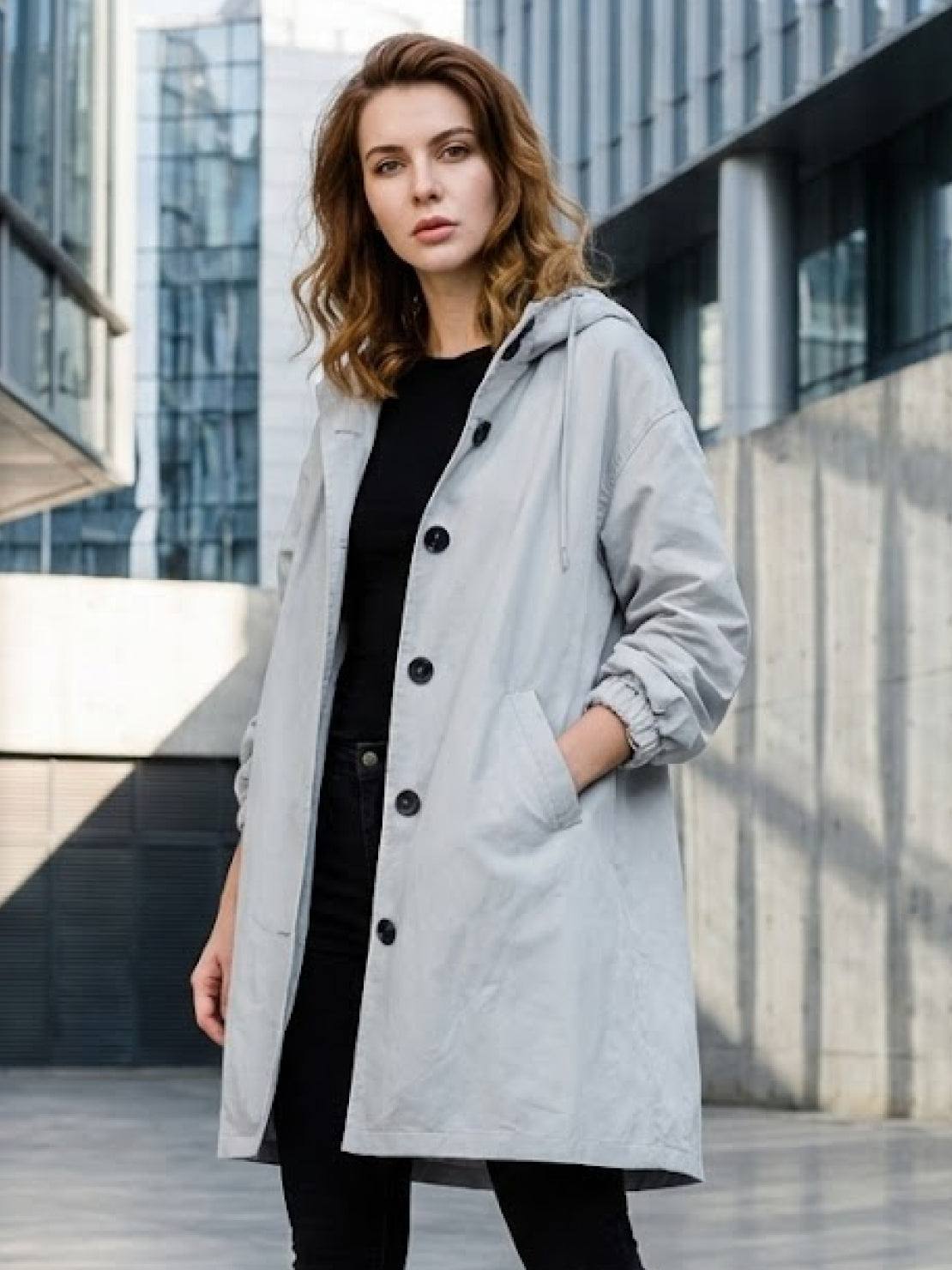 Water-resistant oversized hooded windbreaker rain jacket with multiple pockets and adjustable waistline.