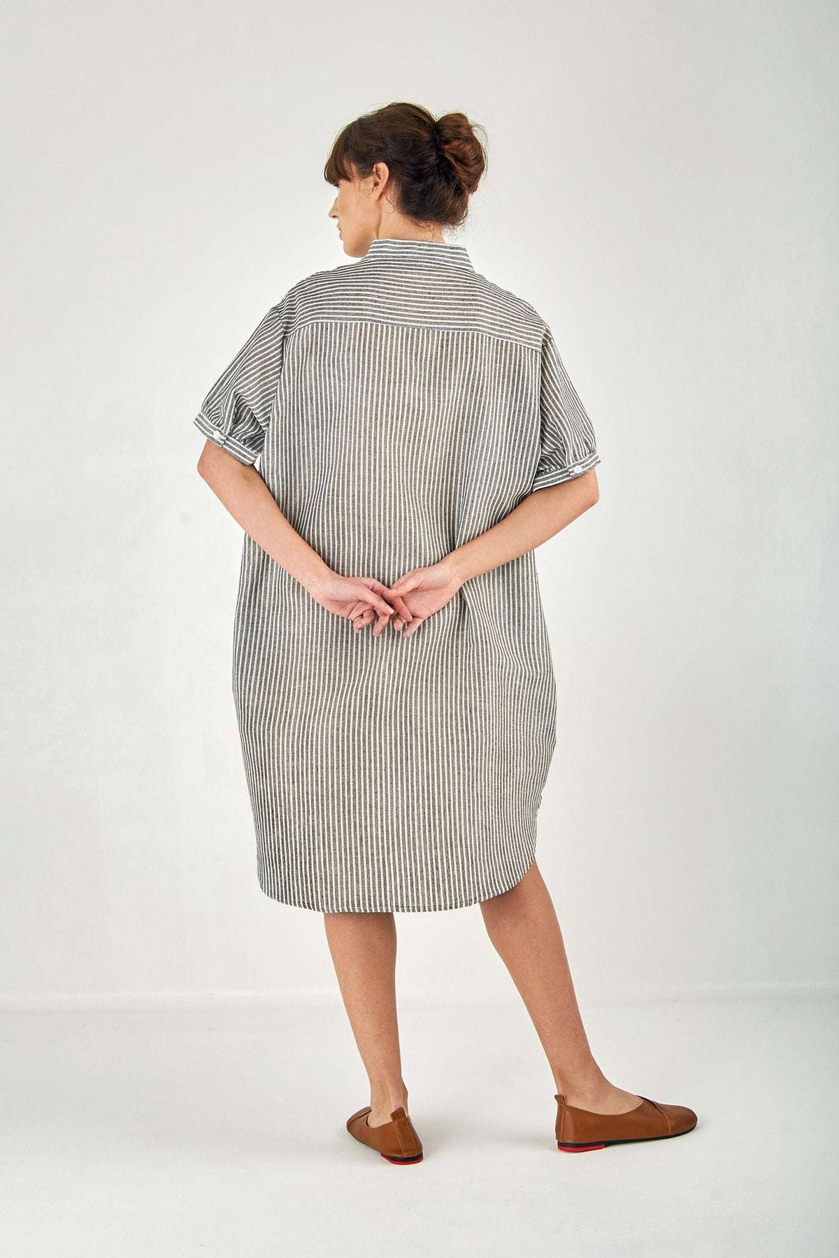 Woman wearing a striped gauze shirt dress made of linen cotton blend, featuring short sleeves and knee length in an oversized fit.