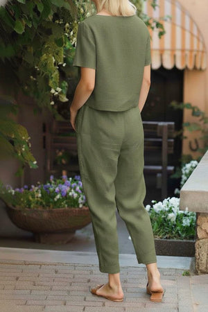 Back view of woman wearing olive green cotton linen set with relaxed short sleeve top and straight-leg pants outdoors