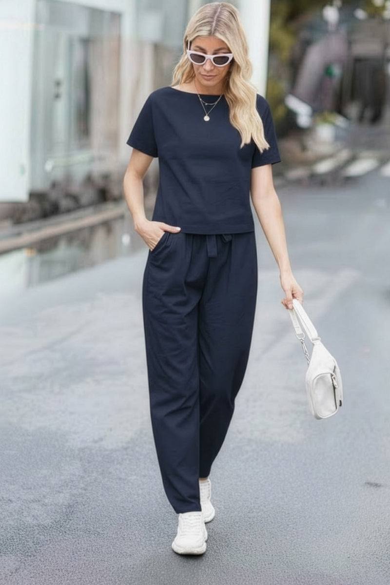 Woman wearing navy cotton linen set with short-sleeve top and straight-leg pants walking on street
