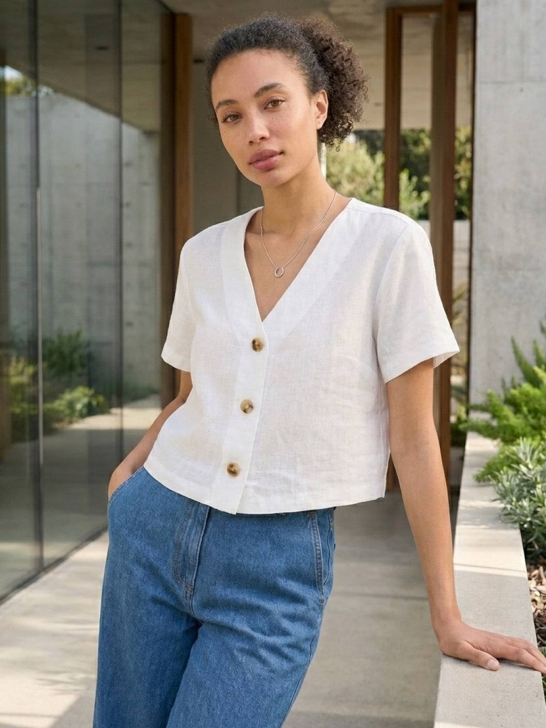 Lightweight 100% linen French top with V-neckline, short sleeves, three buttons, relaxed boxy fit, and cropped hem in light khaki and off white colors