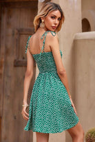 Woman wearing green bohemian skater polka dot dress with sling knot straps outdoors