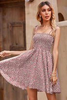 Woman wearing a brown and white polka dot bohemian skater dress with sling knot straps and elastic top, posing outdoors