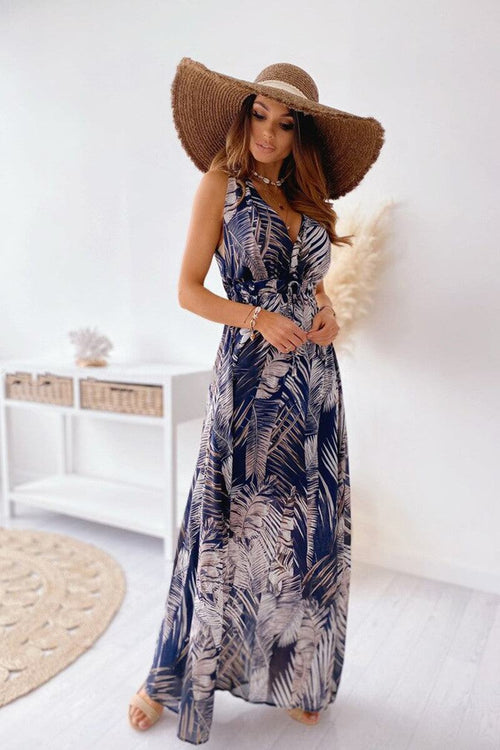 Woman wearing a casual sleeveless print strap dress with tropical leaf pattern and wide-brimmed hat indoors