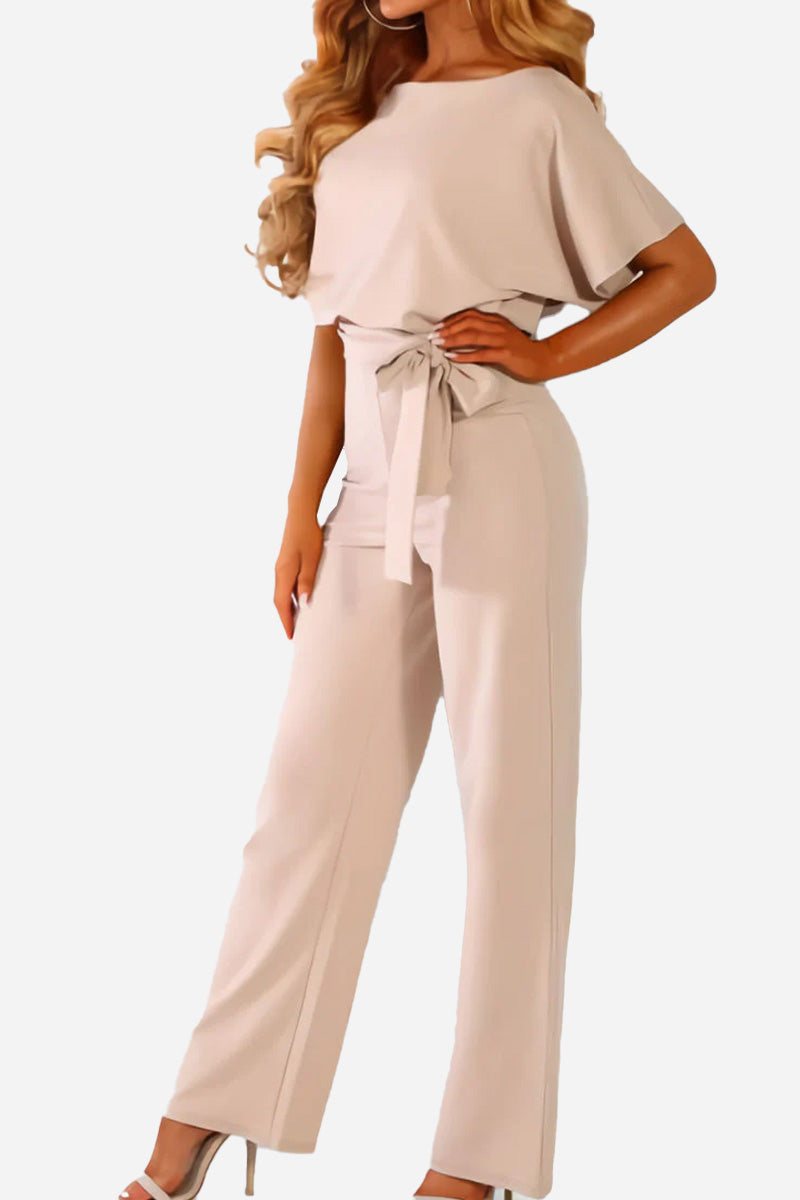 Woman wearing chic short-sleeved wide-leg jumpsuit with belt in light beige color