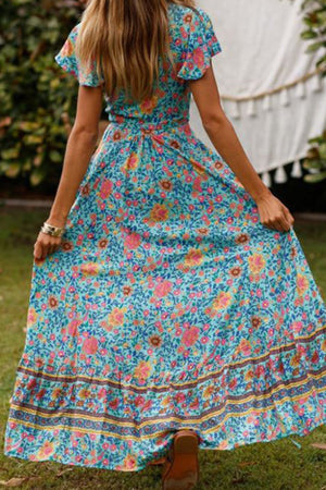 Woman wearing Bohemian floral print wrap dress in blue with colorful flowers outdoors