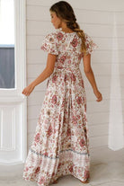 Woman wearing a Bohemian floral print wrap dress with short sleeves and tied waist, standing indoors.