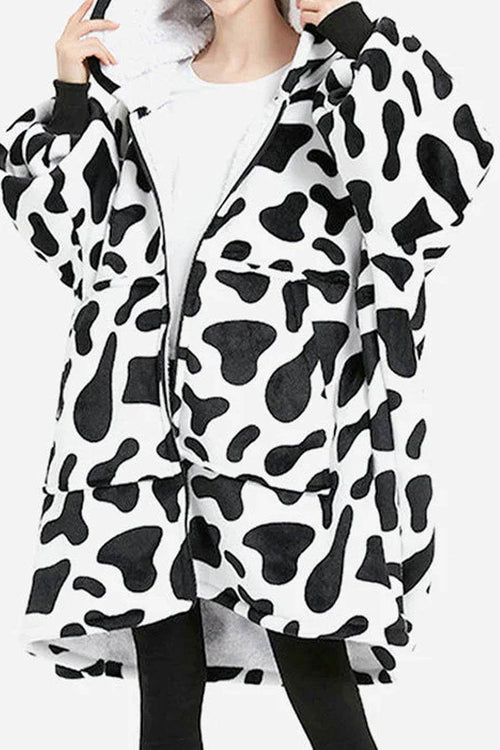 Oversized ultra soft hooded blanket with black and white cow print, front zipper, large pocket, and cozy hood