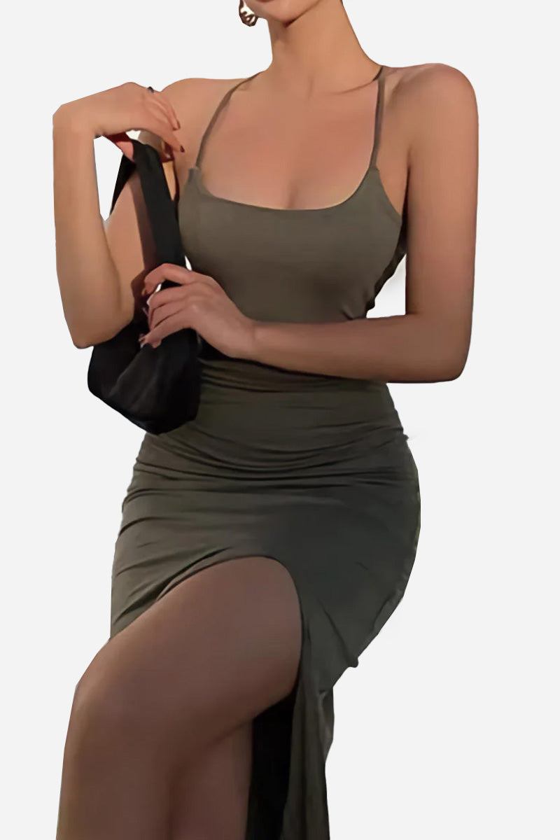 Woman wearing an elegant side slit midi dress with thin straps holding a small black purse against a white background