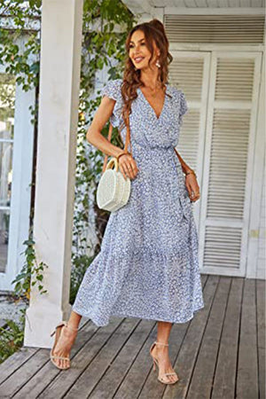 Woman wearing Elegant Blossoms Boho Maxi Dress with floral print, V-neck, short sleeves, and belted ruffle hem, holding a round white handbag.