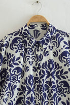 blue floral lantern sleeves pattern close-up on button-up dress collar hanging on wooden hanger