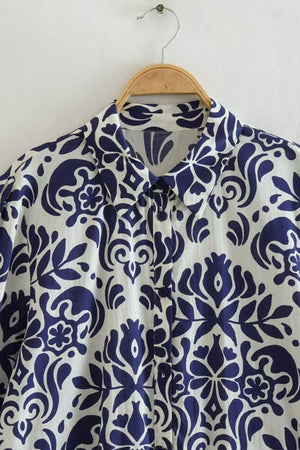 blue floral lantern sleeves pattern close-up on button-up dress collar hanging on wooden hanger