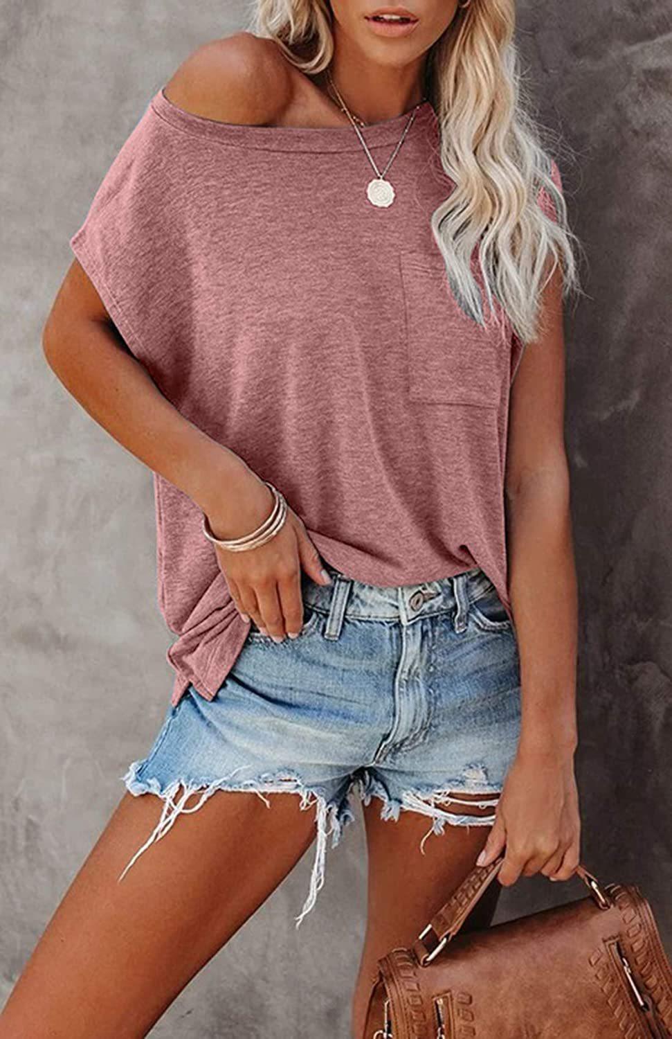 Woman wearing a relaxed fit, lightweight Easy Breezy Tunic Shirt in pink with cap sleeves and front pocket paired with denim shorts