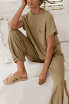 Woman wearing a beige Comfy Couture Knit Sweater two-piece set with knit pullover and high-waisted pants sitting indoors