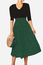 Woman wearing effortlessly chic polka dot pleated midi skirt with high waist and black top holding bamboo handbag