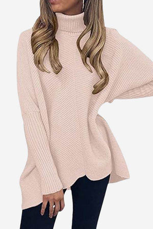 Woman wearing a blush pink cozy oversized knit pullover with long sleeves and turtleneck collar.