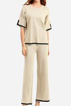 Short sleeved relaxed fit two-piece lounge set with black trim on beige short sleeve top and wide-leg pants