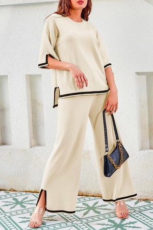 Woman wearing a beige short sleeved relaxed fit lounge two-piece set with black trim, styled with a black handbag and open-toe heels.