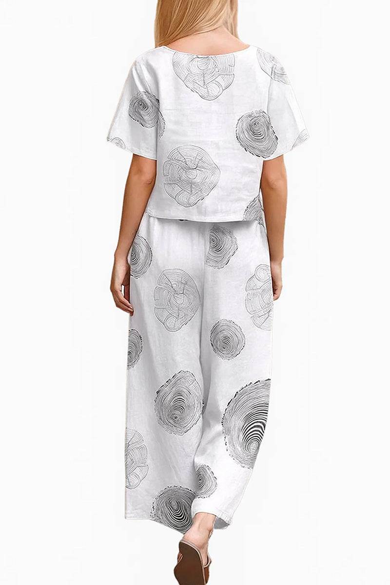 Woman wearing white loose fit co-ord set with black floral prints and wide-leg pants from back view
