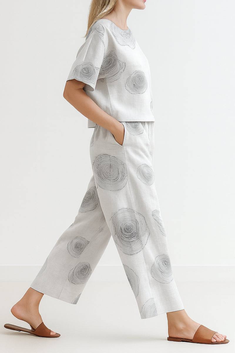 Woman wearing light grey loose fit co-ord set with wide-leg pants and short-sleeve top, featuring subtle circular floral prints.