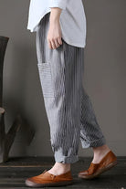Woman wearing high waist striped black and white comfort pants with side pocket and rolled cuffs.