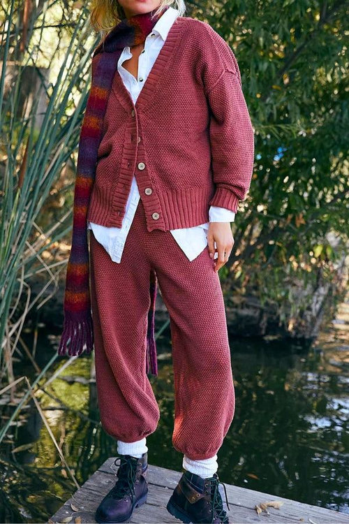 Woman wearing a relaxed two-piece knitwear co-ord set in rust color with buttoned cardigan and jogger pants outdoors