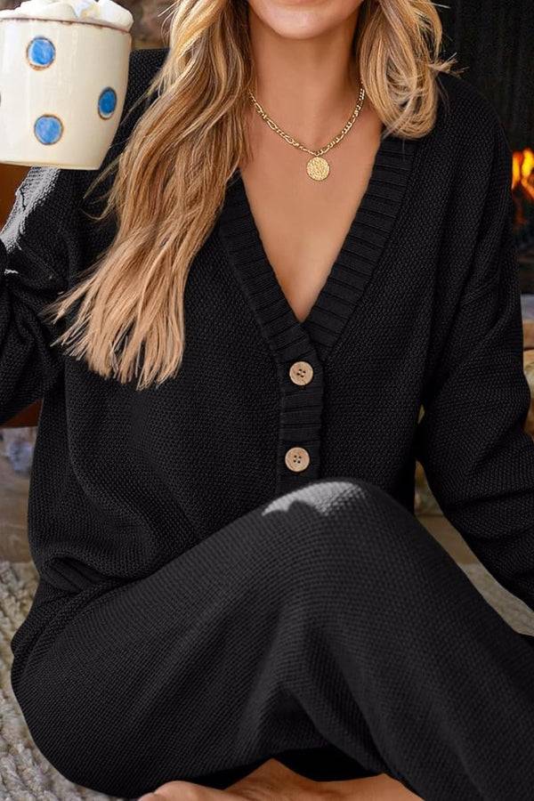 Woman wearing black two-piece knitwear relaxed co-ord set with button front sweater and matching pants holding a mug