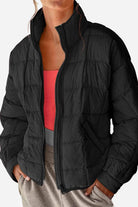Black lightweight puffer travel jacket with quilted design, standing collar, and zipper front.