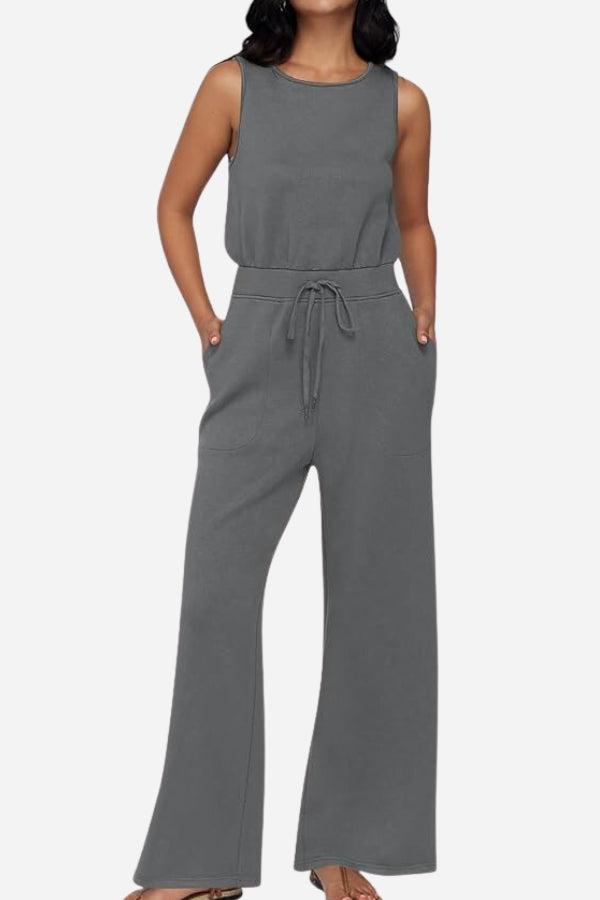 Woman wearing a gray sleeveless wide leg pants jumpsuit with drawstring waist and pockets