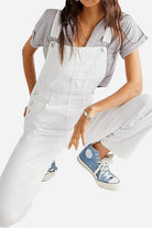 White denim-look tapered-leg adjustable bib overalls styled with a striped shirt and blue high-top sneakers