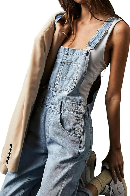 Woman wearing denim-look tapered-leg adjustable bib overalls with beige blazer over shoulder