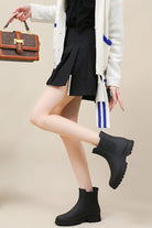 Black non-slip rain boots worn with skirt and cardigan for stylish wet weather protection