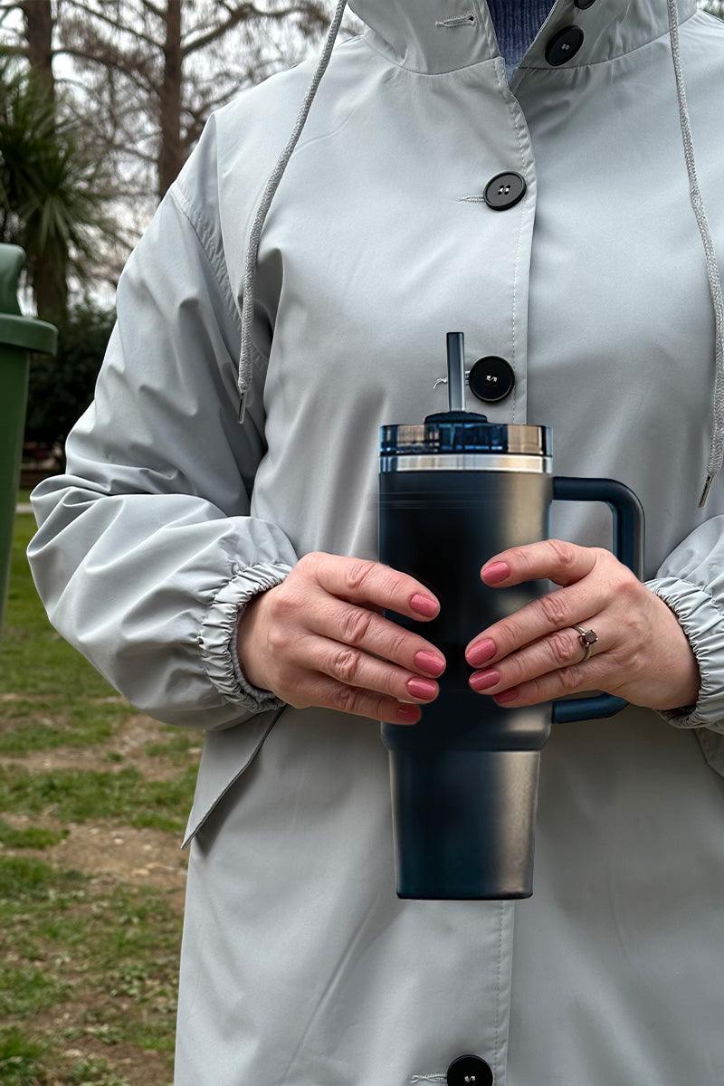 Person holding indestructible travel cup with secure lid and straw outdoors