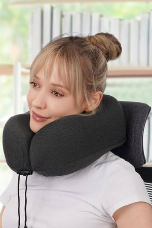 Woman using black memory foam neck pillow from Travel Comfy Kit for comfortable travel rest
