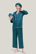 Woman wearing teal classic Mulberry silk pajama set with matching sleep cap and holding a carrying pouch