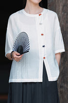Lightweight white regenerated cellulose blouse with asymmetrical multicolor buttons, oversized fit, and breathable fabric.