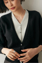 Woman wearing a black and white single-breasted cashmere wool cardigan with relaxed fit and button closure
