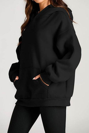 Black oversized fleece-lined hoodie with front pocket and relaxed fit for cozy travel wear