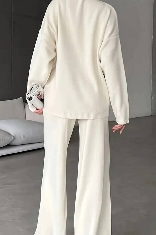 Back view of a woman wearing a cream knitted turtleneck two-piece set with wide-leg pants in a modern living room.