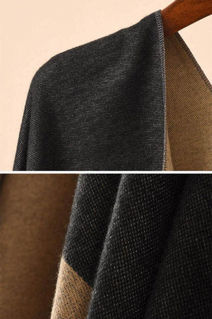 Two-tone elegant knitted poncho in black and brown with a flowing silhouette hanging on wooden hanger