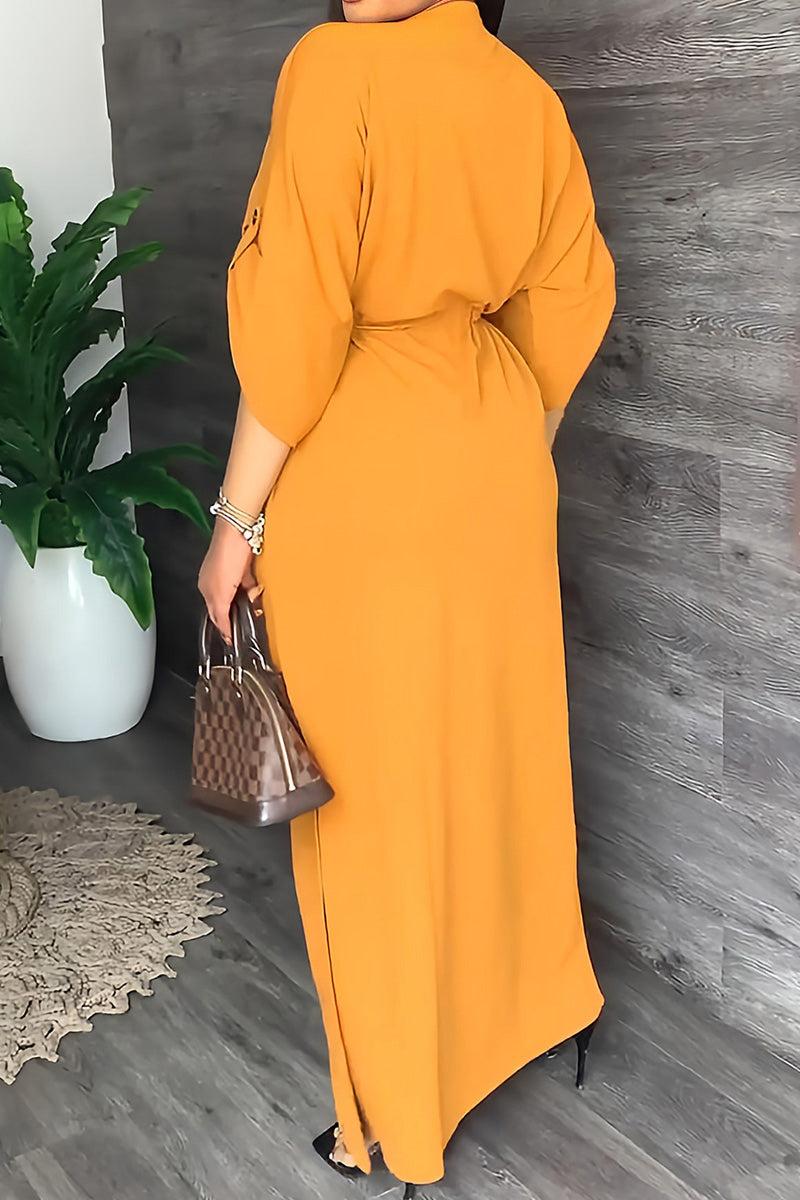 Woman wearing mustard yellow All-Day Drape Dress with cinched waist and rolled-up sleeves, holding a brown handbag.