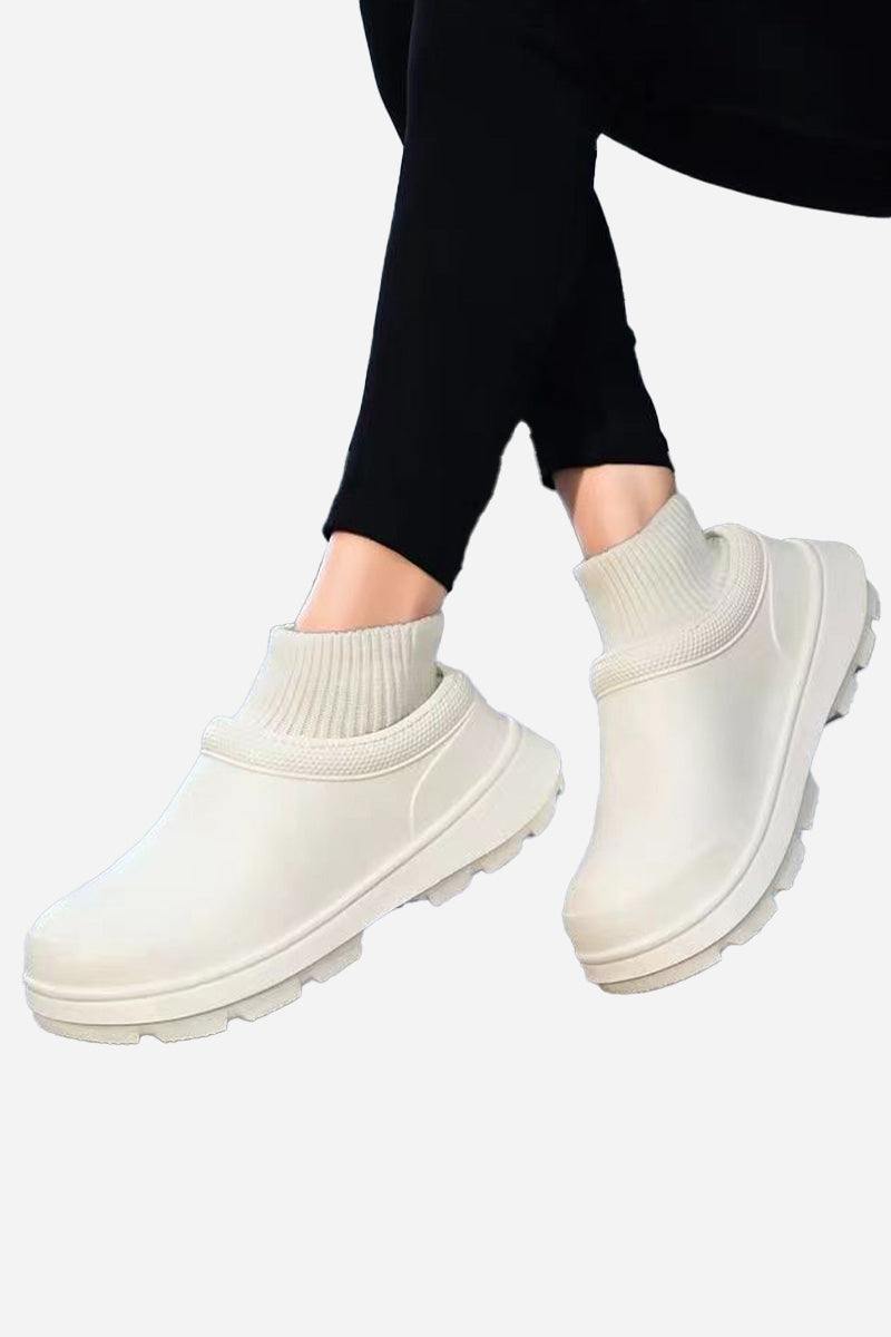 White fleece-lined comfort clogs with waterproof exterior and textured sole worn with black leggings