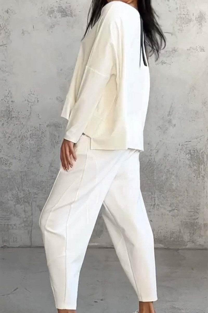 Woman wearing an off-white All-Day Comfort 2-Piece Outfit Set with loose-fit top and tapered pants against a concrete wall background