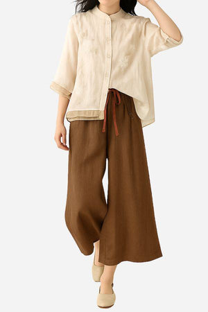 Woman wearing Cotton Linen Tuscany 2-piece set with sheer embroidered top and wide-leg brown linen pants