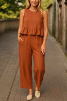 woman wearing rust-colored sleeveless linen-like feel set with wide-leg pants and ruffle top outdoors